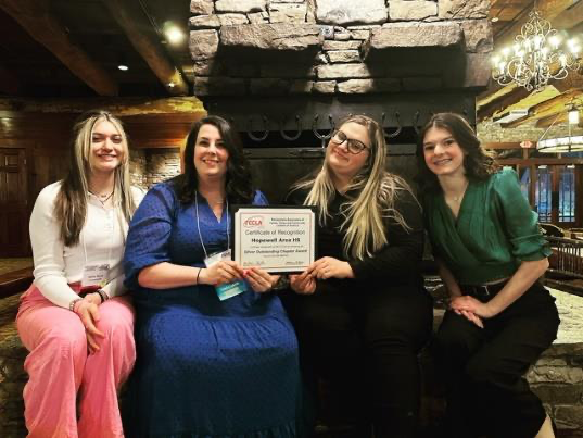 Students and teacher sitting holding a certificate